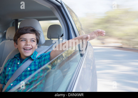 Happy boy sticking hand out window of car Stock Photo