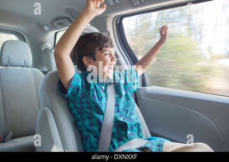 Enthusiastic boy cheering in back seat of car Stock Photo