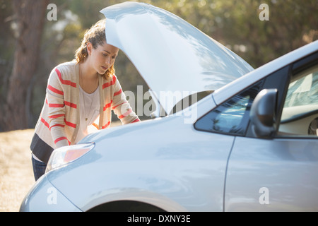 Woman checking car engine at roadside Stock Photo