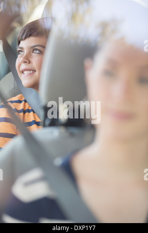Happy boy looking at window from back seat of car Stock Photo