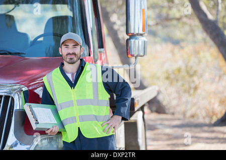 Portrait of confident roadside mechanic leaning on truck Stock Photo