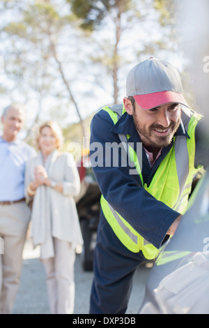 Senior couple watching roadside mechanic push car Stock Photo