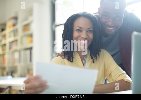 Portrait of happy couple with paperwork at laptop Stock Photo