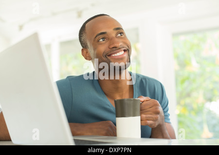 Happy man drinking coffee at laptop Stock Photo