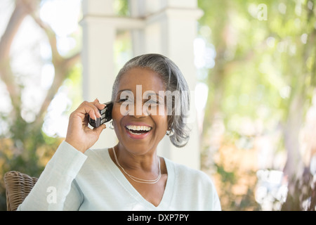 Enthusiastic senior woman talking on telephone on porch Stock Photo