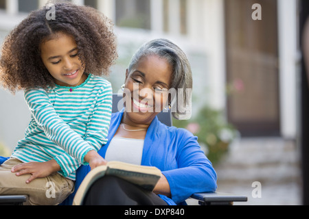Grandmother and granddaughter reading book on patio Stock Photo