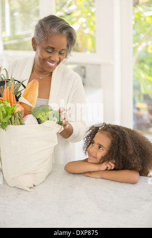 Grandmother and granddaughter unpacking groceries in kitchen Stock Photo