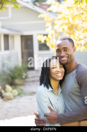 Portrait of smiling couple hugging outside house Stock Photo