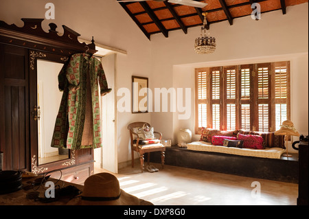 Robe hangs on embossed wardrobe and window seat with shutters closed, Indian state of Goa Stock Photo