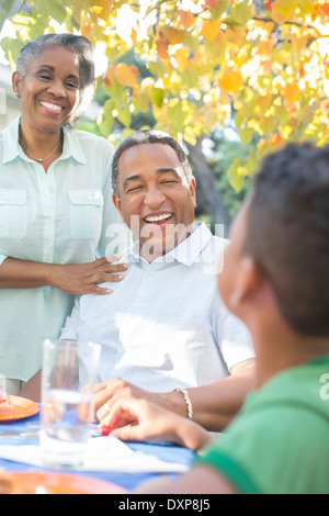 Grandparents and grandson laughing at patio table Stock Photo