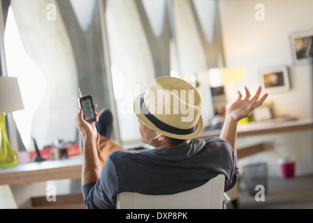 Casual businessman talking on cell phone with feet up on desk Stock Photo