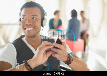 Casual businessman listening to music on headphones with mp3 player Stock Photo