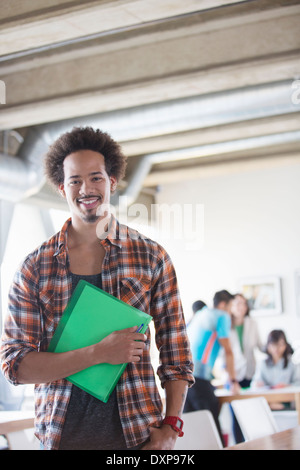 Portrait of confident casual businessman holding folder in office Stock Photo