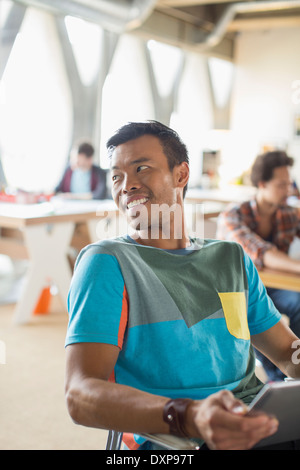 Happy casual businessman looking over shoulder in office Stock Photo