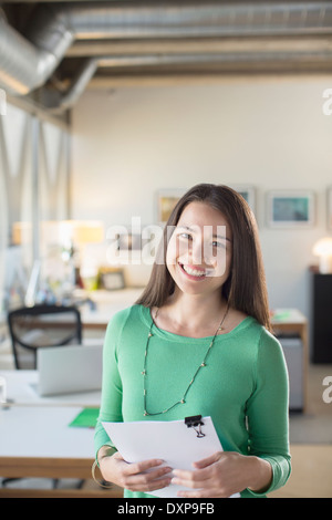 Portrait of smiling businesswoman holding paperwork in office Stock Photo