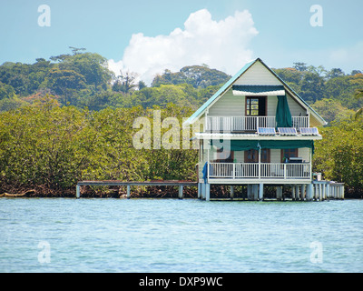 House on stilts over water with solar panels and dense tropical vegetation in background, Bocas del Toro, Caribbean sea, Panama Stock Photo