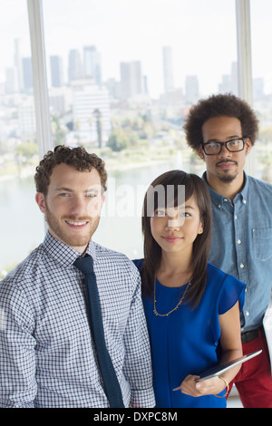 Portrait of confident business people at window overlooking city Stock Photo