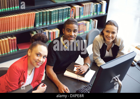 Diverse group of young students working on computer in a public library. Young people finding information on the Internet. Stock Photo