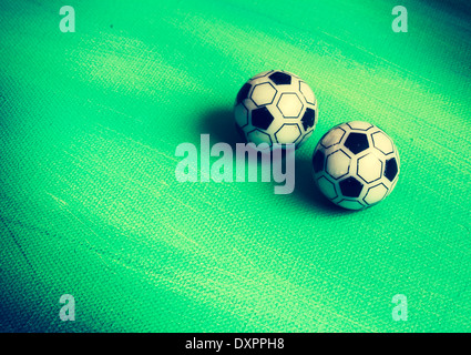 Two toy footballs on green canvas filter. Stock Photo