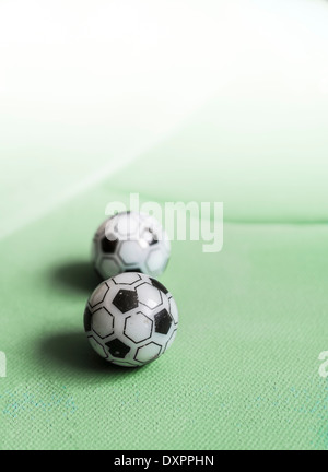 Two toy footballs in lineup on green canvas fading out to white. Vertical image with copy space. Stock Photo