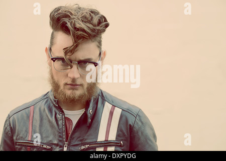 A bearded man in pompadour vintage hairstyle and vintage glasses head and shoulder portrait, an edgy vintage concept Stock Photo