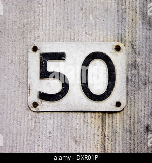 House number fifty embossed in a metal plate. Black lettering on a white background Stock Photo
