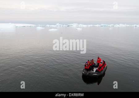 Antarctica cruise ship tourism among the landscape of Antarctic iceberg, icebergs, glacier, and ice with tourists in zodiac. Stock Photo