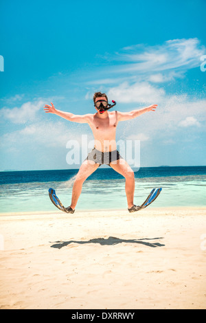 Funny man jumping in flippers and mask. Holiday vacation on a tropical beach at Maldives Islands. Stock Photo