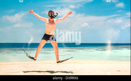Funny man jumping in flippers and mask. Holiday vacation on a tropical beach at Maldives Islands. Stock Photo