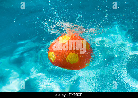 Beach ball splashing in a swimming pool. Stock Photo