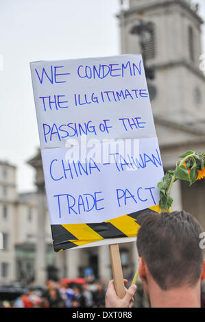 Trafalgar Square, London, UK. 30th March 2014. Taiwanese protester holding a banner and sunflowers at a protest in Trafalgar Square against the China-Taiwan trade pact, fearing it may affect democracy. Credit:  Matthew Chattle/Alamy Live News Stock Photo