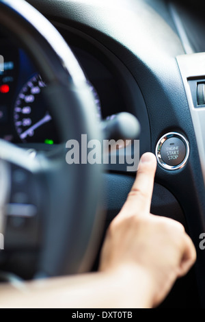 finger pressing the Engine start stop button in car Stock Photo