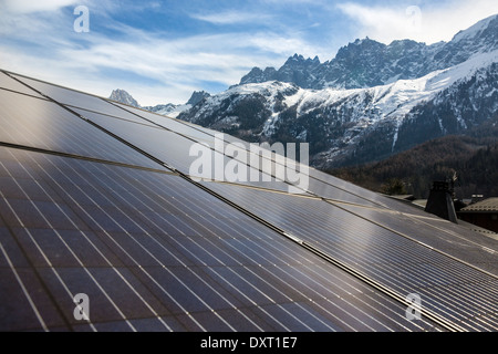 Solar panels on part of a roof in the French alps, mountains in background, the Aiguilles de Chamonix in Chamonix France. Stock Photo