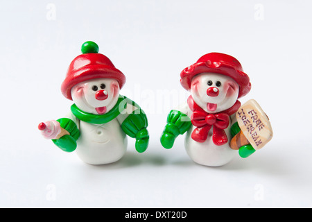 Two cute clay snowmen wearing red & green holiday garments , giving away free ice cream in the winter. Stock Photo