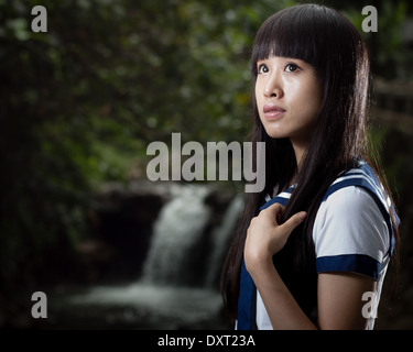 Cute Chinese schoolgirl with waterfall in background Stock Photo