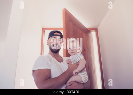 Portrait of smiling father holding baby son in doorway Stock Photo