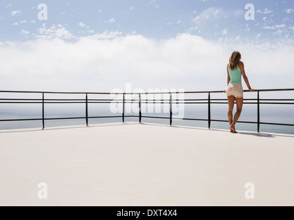 Woman standing on balcony overlooking ocean Stock Photo