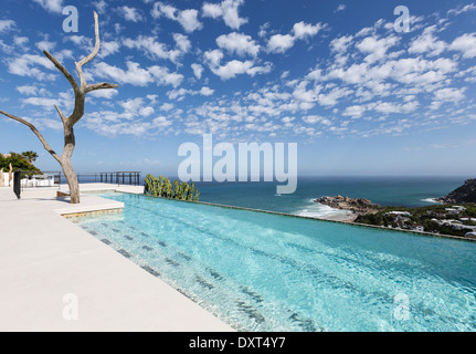 Clouds in blue sky over luxury lap pool overlooking ocean Stock Photo