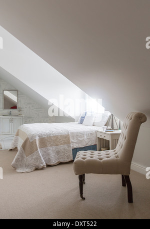 Bed under window in attic bedroom Stock Photo