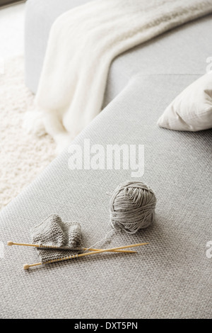 Knitting needles and ball of wool on sofa Stock Photo