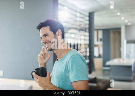 Happy man talking on cell phone and drinking coffee at home Stock Photo
