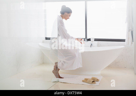 Woman in bathrobe preparing bath Stock Photo