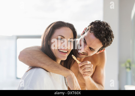 Man trying to brush womanÍs teeth in bathroom Stock Photo