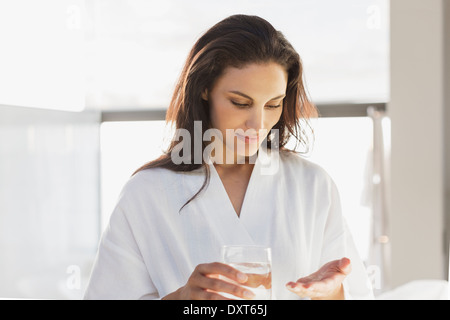 Woman in bathrobe taking medication in bathroom Stock Photo