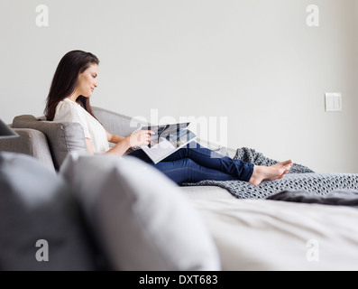 Woman reading magazine on chaise lounge Stock Photo