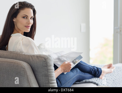 Portrait of confident woman reading magazine on chaise lounge Stock Photo