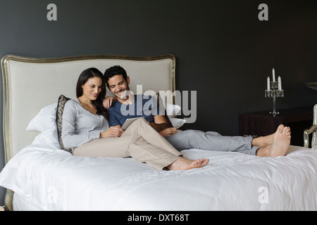 Couple using digital tablet in bedroom Stock Photo