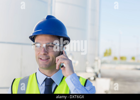 Close up of worker talking on cell phone in front of silage storage tower Stock Photo