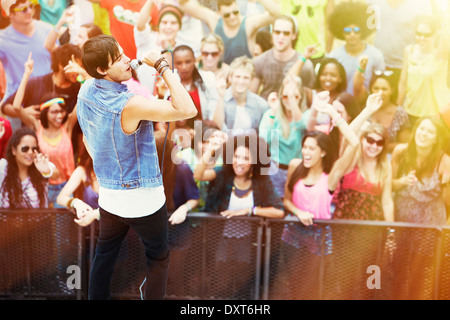 Fans cheering for singer performing on stage at music festival Stock Photo