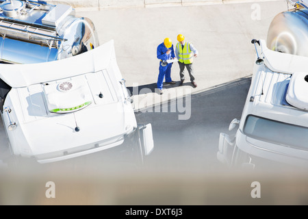 Workers reviewing paperwork near milk tankers Stock Photo